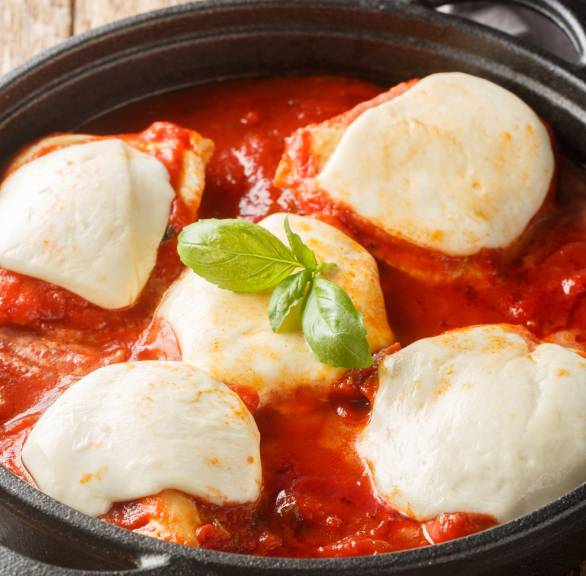 Überbackenes Tomate-Mozzarella-Hähnchen alla Pizzaiola in einer Pfanne garniert mit frischem Basilikum