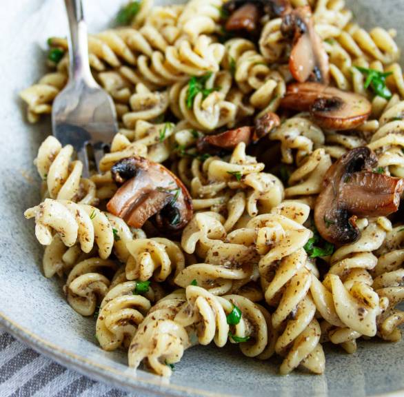 Fusilli mit vegetarischer Carbonara aus Tofu und Pilzen auf einem Teller garniert mit frischer Petersilie