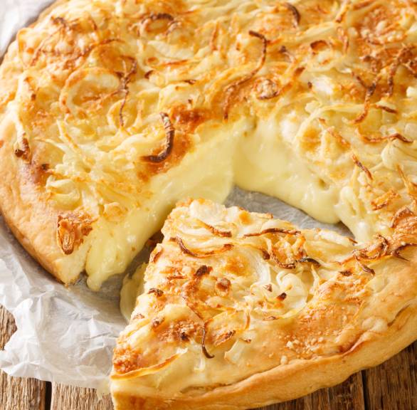 Runde Fugazza angeschnitten mit herauslaufender Füllung aus geschmolzenem Käse getoppt mit Zwiebelringen