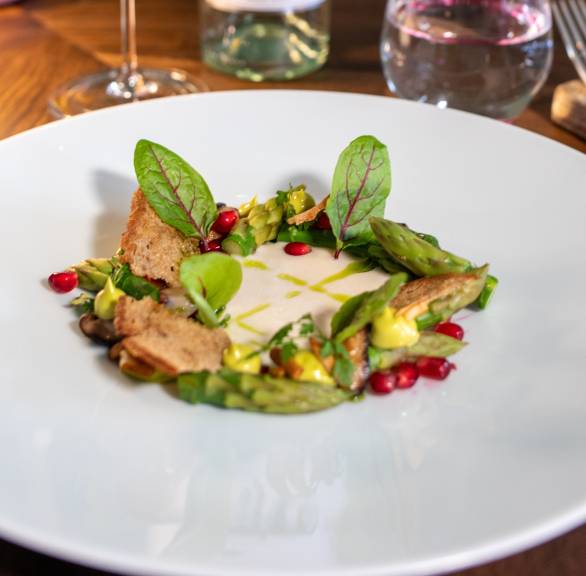 Vorspeise Aus Mandelcreme, grünem Spargel, Austernpilzen und Granatapfelkernen auf einem Tisch im Landhaus Stricker von Holger Bodendorf