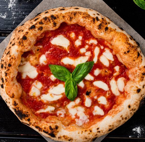 Pizza Napoletana mit Basilikum garniert auf einem Stück Backpapier