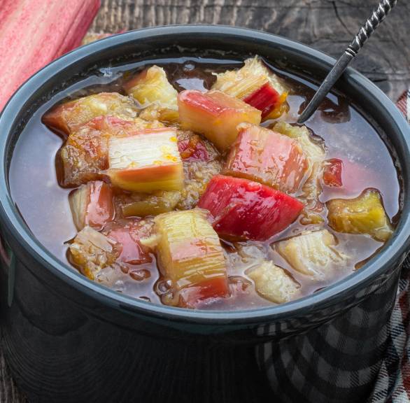 Selbst gekochtes Rhabarberkompott in einer Steingutschale auf einem Holztisch