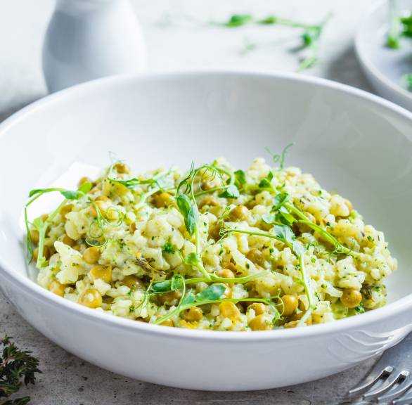 Risi e Bisi Reis mit Erbsen und Parmesan auf einem tiefen Teller garniert mit frischen Kräutern