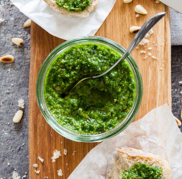 Selbstgemachtes Bärlauchpesto in einem Weckglas, daneben ein Stück Ciabatta, das damit bestrichen wurde