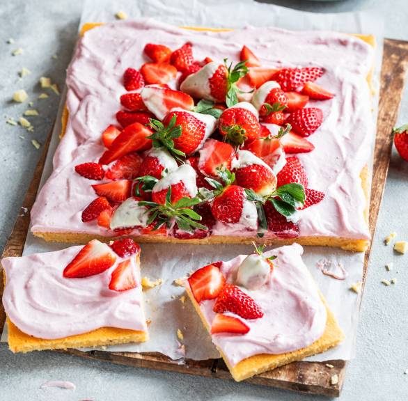 Quark-Erdbeer-Kuchen auf einem Backblech getoppt von teilweise schokolierten frischen Erdbeeren