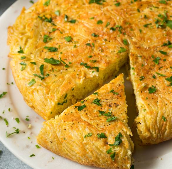 Frittata di pasta aus Spaghetti angeschnitten auf einem Teller bestreut mit frischer Petersilie