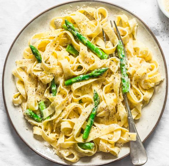 One Pot Spargel Pasta auf einem Teller, daneben ein Schälchen Parmesan