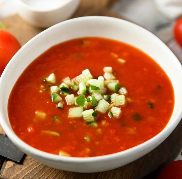 Selbst gemachte Gazpacho in einer Suppenschüssel getoppt mit Gurkenwürfeln