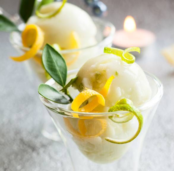 Selbstgemachtes Limoncello Sorbet in zwei Eisbechern dekoriert mit Minze und Zitrone