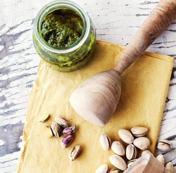Selbst gemachtes Pistazienpesto in einem Glas, daneben Pistazien auf einem Tisch