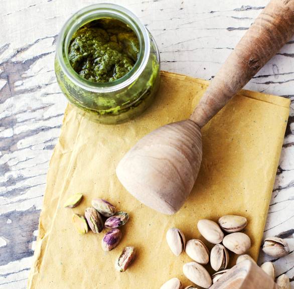 Selbst gemachtes Pistazienpesto in einem Glas, daneben Pistazien auf einem Tisch