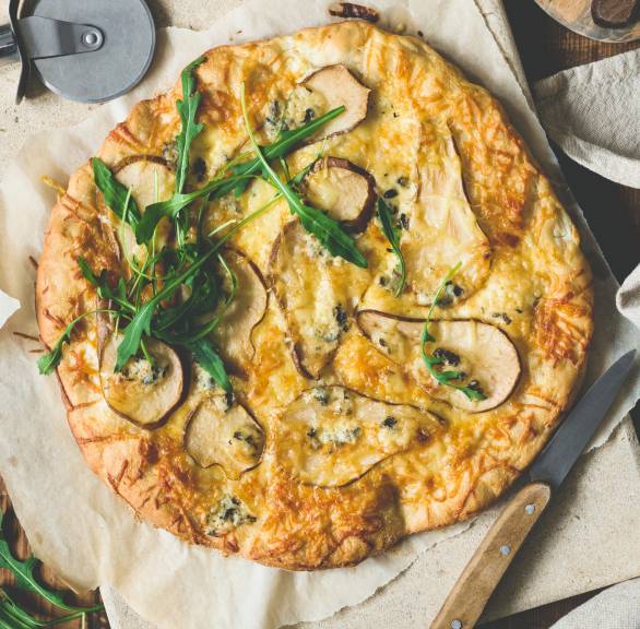 Runde Pizza mit Gorgonzola, Birne und Rucola im Ganzen auf einem Küchentuch