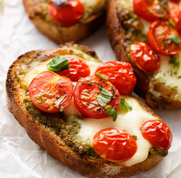 Drei Bruschettas mit geschmolzenem Mozzarella und Tomaten auf einem Teller