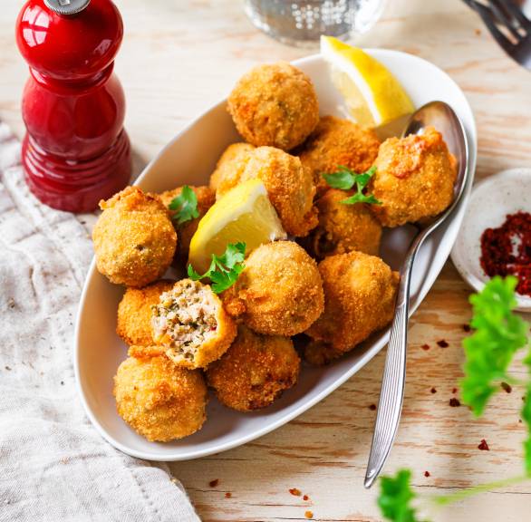Mehrere Polpettine di Tonno frittierte Thunfischbällchen in einer Vorspeisenschale garniert mit Zitronenspalten