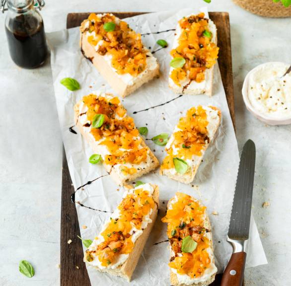Fünf Melonen-Bruschetta mit Feta-Creme angerichtet auf einem Holzbrett
