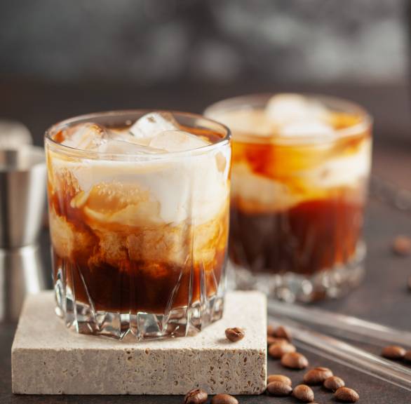 Kaffee-Cocktail mit Sahne und Eiswürfeln in zwei Cocktailgläsern auf einem Tisch