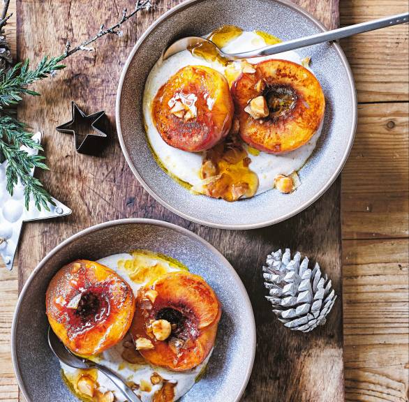 Zwei Portionen veganes Weihnachtsdessert aus gebratenen Pfirsichen auf Zimtjoghurt mit Nusstopping in zwei Dessertschalen