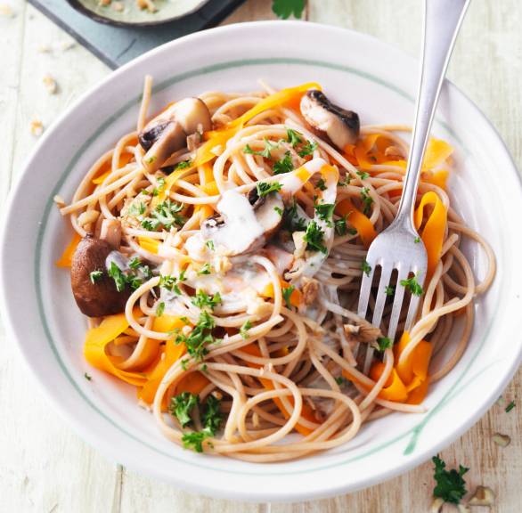 Vollkornspaghetti mit Karotten, Pilzen und Gorgonzola-Sahnesoße angerichtet auf einem Pastateller