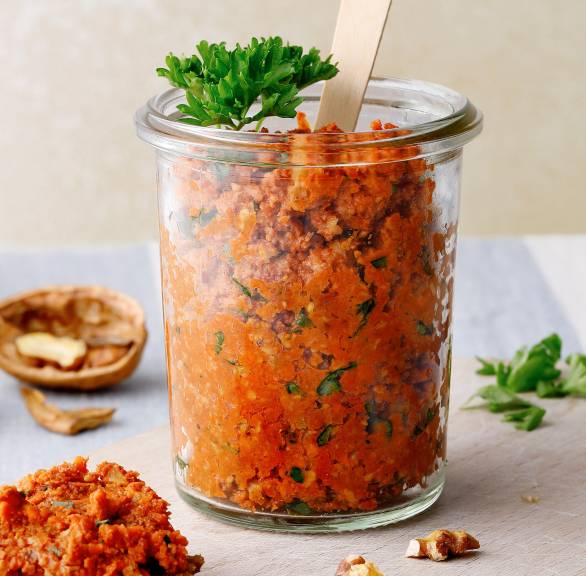 Selbstgemachter italienischer Karottenaufstrich mit Walnüssen in einem Weckglas auf einem Holzbrett