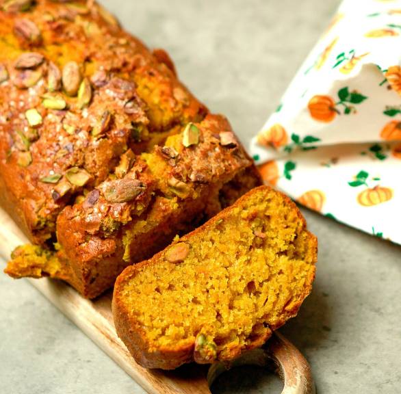 Selbst gebackenes Kürbisbrot mit Pistazien getoppt angeschnitten auf einem Holzbrett