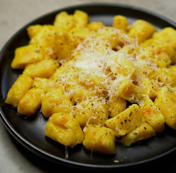 Selbstgemachte Kürbisgnocchi auf einem Teller bestreut mit Parmesan