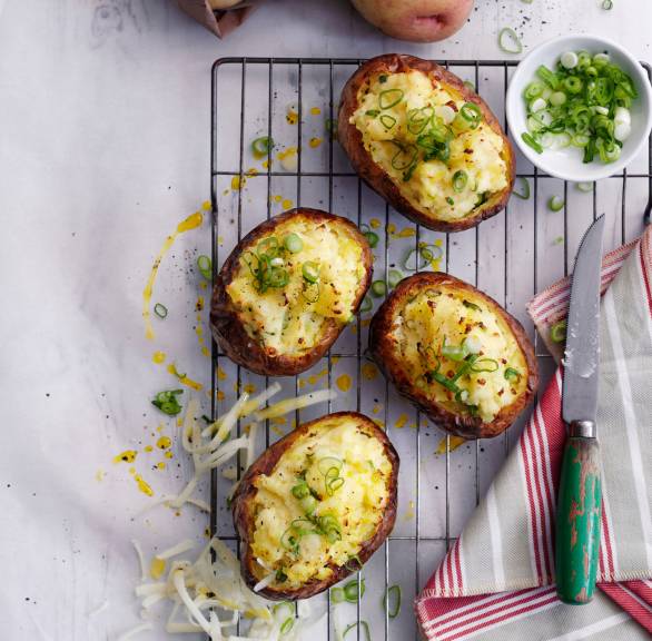 Gebackene Ofenkartoffeln mit Käsefüllung und Frühlingszwiebelröllchen auf einem Backrost