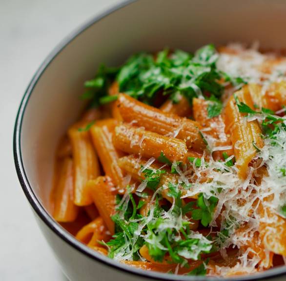 Penne in Tomaten-Wodka-Sauce getoppt mit Parmesan und frischer Petersilie in einem Kochtopf