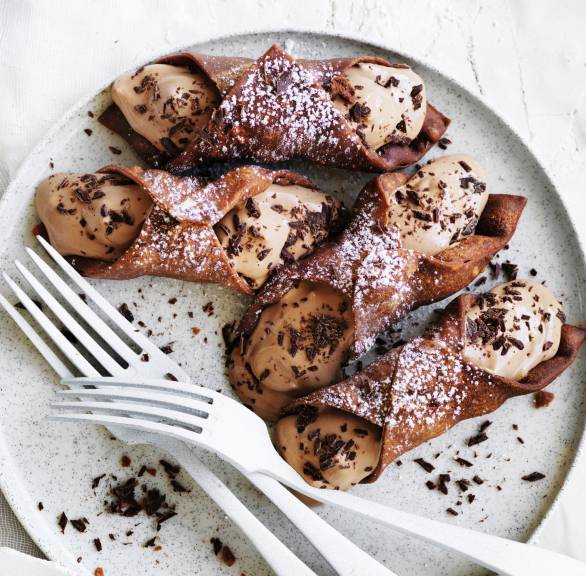 Selbst gemachte Schoko-Cannoli gefüllt mit Ricotta-Schokocreme-Füllung auf einem Dessertteller