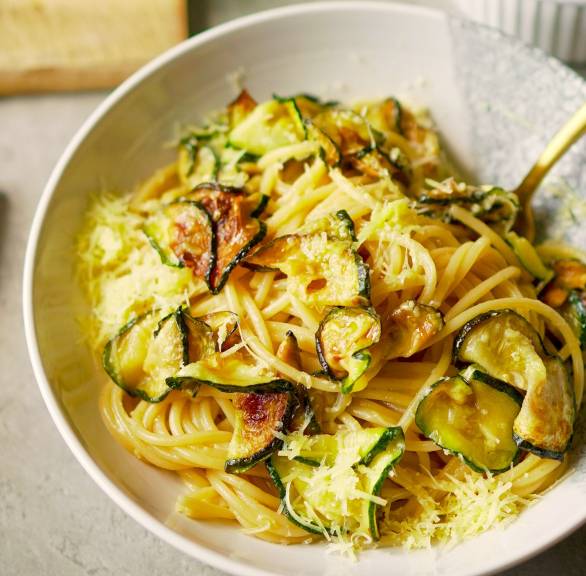Spaghetti alla Nerano mit Zucchinischeiben und Parmesan in Sauce auf einem tiefen Teller