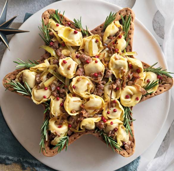 Sternfürmige Quiche mit Tortellini-Salsiccia-Füllung festlich garniert auf einer Platte