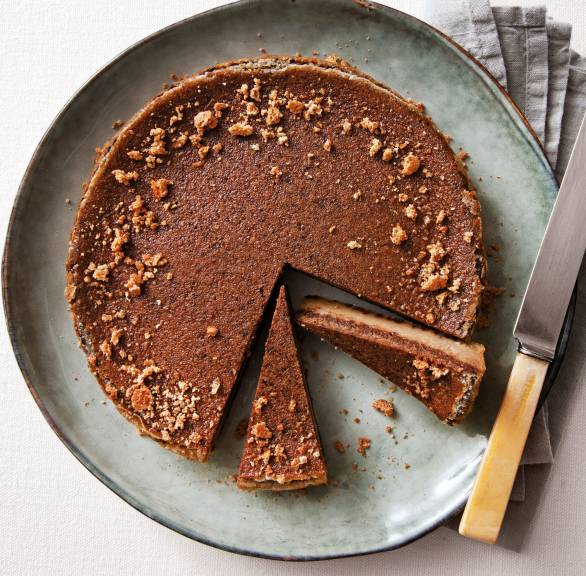 Runder Schokoladenkuchen mit Schichten angeschnitten auf einer Kuchenplatte verziert mit Amarettini-Krümeln