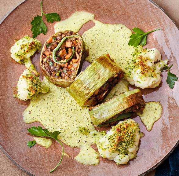Vegane Lauch-Roulade mit Linsenfüllung in Stücken angerichtet auf einem Teller mit selbstgemachter Pistaziensoße