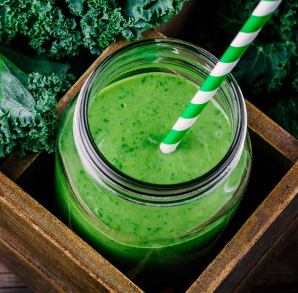 Grünkohl-Smoothie mit Apfel und Ingwer in einem Weckglas auf einem Holztisch