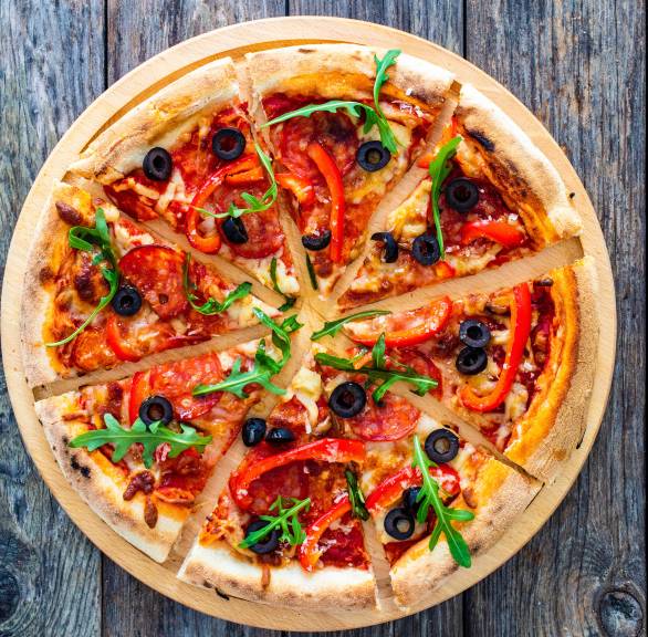 Runde Pizza in Pizzastücke geschnitten mit Nduja-Salami, Oliven, Mozzarella und Rucola belegt auf einem Tisch