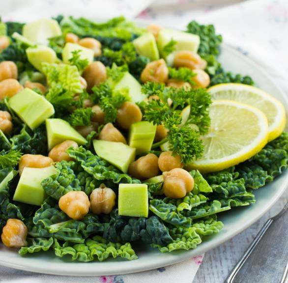 Wirsingsalat mit Avocado und Kichererbsen auf einem Teller, daneben Joghurt-Dressing