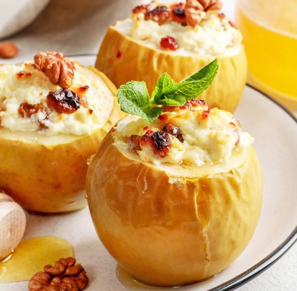 Drei Bratäpfel mit Zimtquark-Nussfüllung angerichtet auf einem Dessertteller getoppt von Walnüssen und Honig