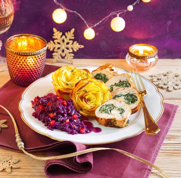 Gefüllte Hähnchenbrust mit Ricotta-Spinat-Füllung angerichtet mit Kartoffelrosen und Granatapfel-Rotkohl auf einem Teller