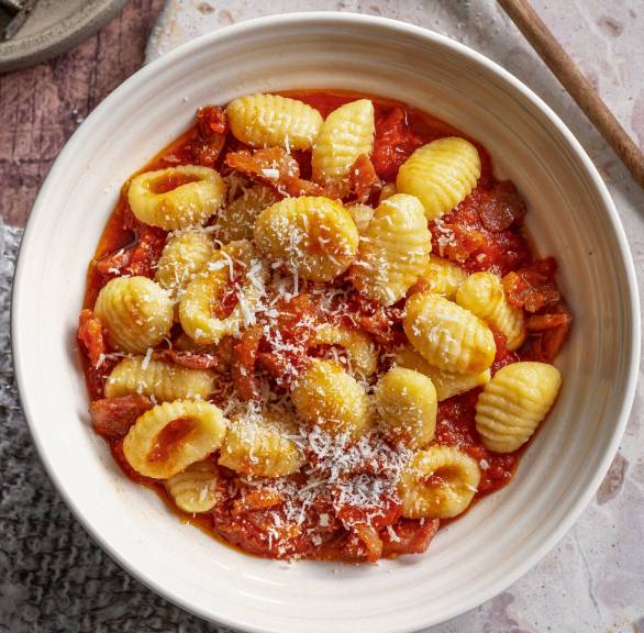 Gnocchi mit all'amatriciana Soße angerichtet auf einem Pastateller getoppt von frischem Parmesan