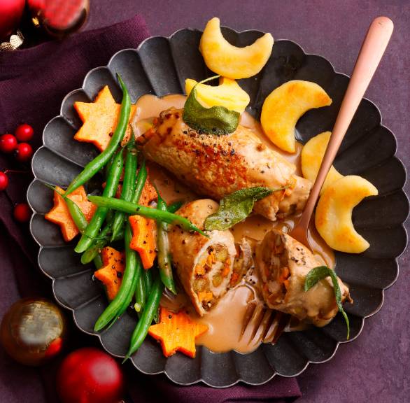 Angeschnittene, gefüllte Involtini angerichtet mit Polentamonden, Süßkartoffelsternen, grünen Bohnen und Sauce auf einem Teller