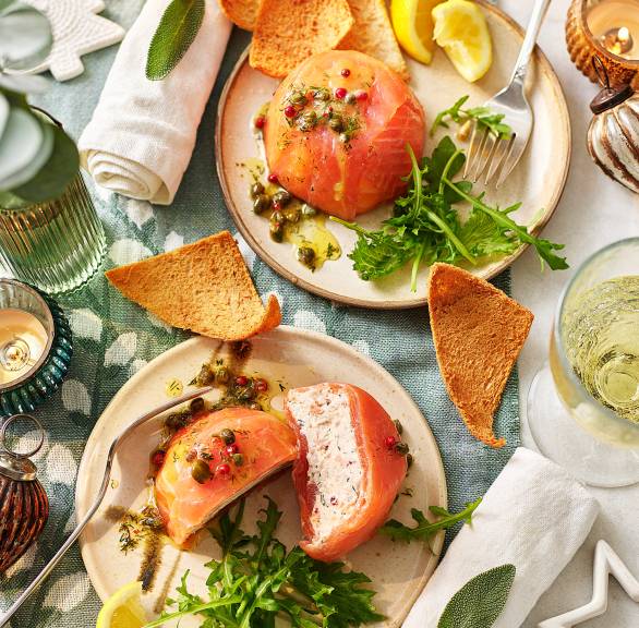 Zwei selbstgemachte Lachsterrinen angerichtet auf Vorspeisentellern, eine halbiert und Frischkäse-Lachs-Füllung sichtbar