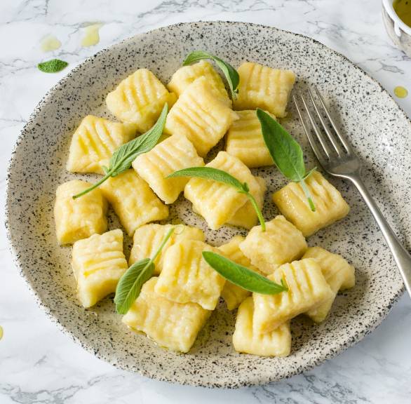Selbstgemachte Quark-Gnocchi angerichtet mit Salbeibutter auf einem Pastateller