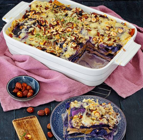 Rotkohl-Lasagne mit Champignons angeschnitten in einer Auflaufform getoppt mit käse und Haselnusskernen