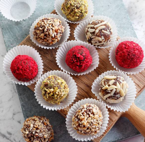 Selbstgemachte Dattelpralinen in Pralinenkapseln auf einem Holzbrett