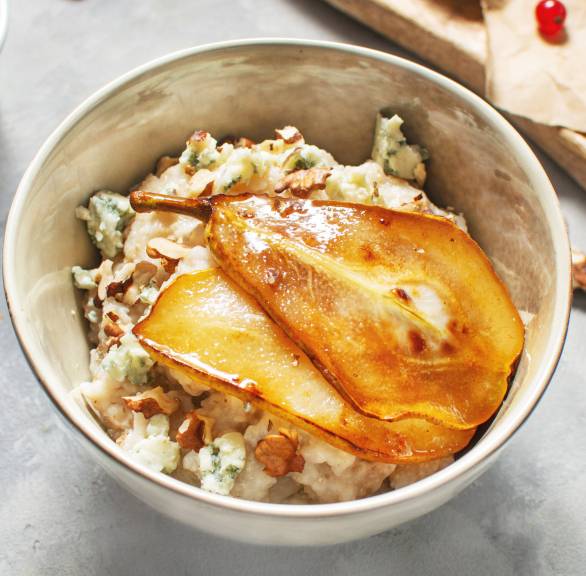 Walnussrisotto mit Gorgonzola getoppt von zwei Scheiben karamellisierter Birne in einer Schale