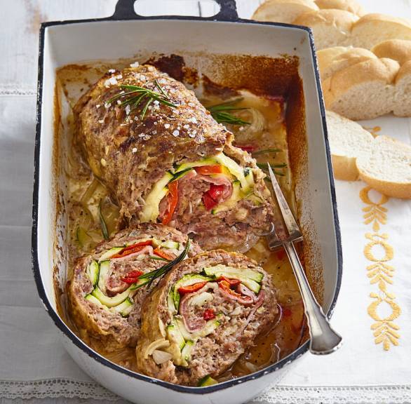 Gefüllter italienischer Hackbraten mit Zucchini und Paprika auf geschmorten Zwiebeln und Pancetta in einem Bräter