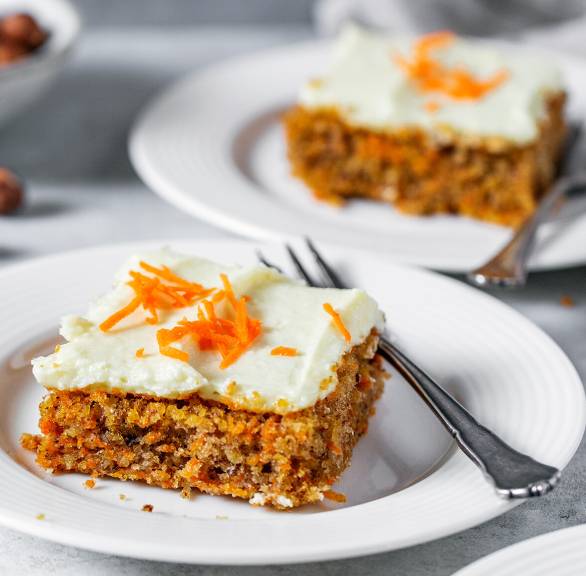Drei Stücke Karottenkuchen vom Blech mit Frischkäse-Frosting auf Kuchentellern