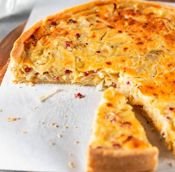 Runder Zwiebelkuchen mit Mürbeteig ohne Hefe angeschnitten auf einem Teller