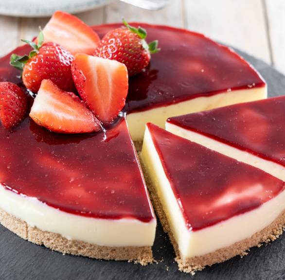 Runder Erdbeer-Panna cotta Cheesecake ohne Backen angeschnitten auf einer Schieferplatte