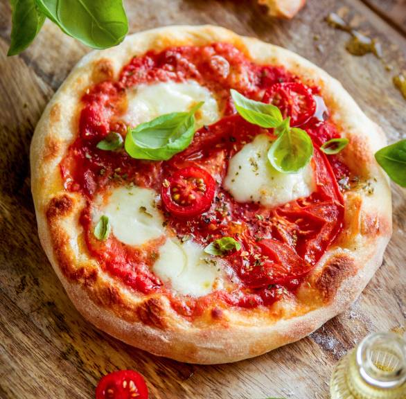 Zwei italienische Pizzette Margherita Mini-Pizzen garniert mit frischem Basilikum auf einem Holzbrett 