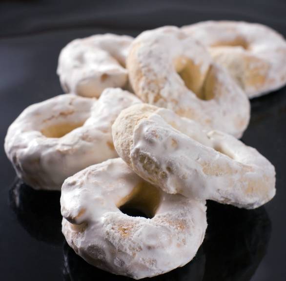 Mehrere selbstgebackene Taralli Osterplätzchen mit Zuckerguss auf einem Teller